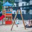 Bird Nest Swing with Tower (BNS 120 cm) laste mänguväljakul liivapinnal kiikumas.