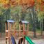 Mini Play Modern Nature laste mänguväljak kiige, ronimisseina ja liuväljaga sügisese metsa taustal.