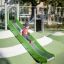 Laste mängib Hill Slide SL120 liumäel värvilisel mänguväljakul.