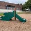 Slide with Dragon Back lasteaia liugraud, roheline ja pruun, liivapõhjal.