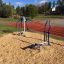 Väljas Cross Trainer treeningseade mänguväljakul, punase jooksurada taustal.